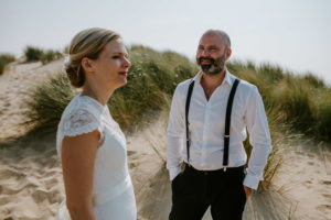 Brautpaar am Strand, umgeben von Dünen – Hochzeitsreportage NRW mit natürlichem Stil.