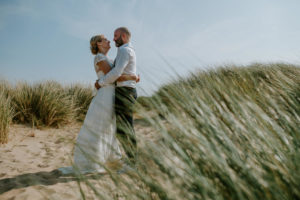 Brautpaar steht entspannt auf sandigen Dünen mit Blick in die Ferne – Hochzeitsfotografin Köln.