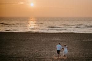Brautpaar läuft am Strand in der Abendsonne – natürliche Hochzeitsfotografie NRW, warm und echt.