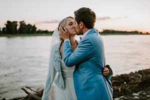 Braut und Bräutigam teilen einen Kuss am Rhein bei Sonnenuntergang – Hochzeitsfotografin Köln.