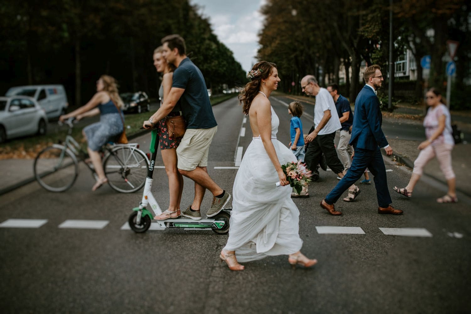 Die Braut im weißen Kleid überquert den Zebrastreifen – echte Momente in Köln eingefangen.