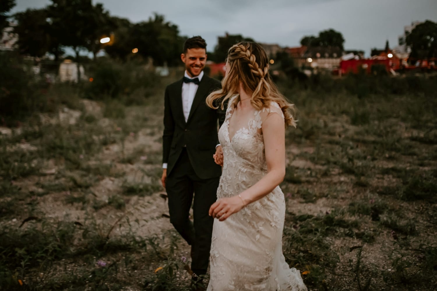 Brautpaar geht Hand in Hand über eine grüne Wiese – Hochzeitsreportage NRW, natürlich und echt.