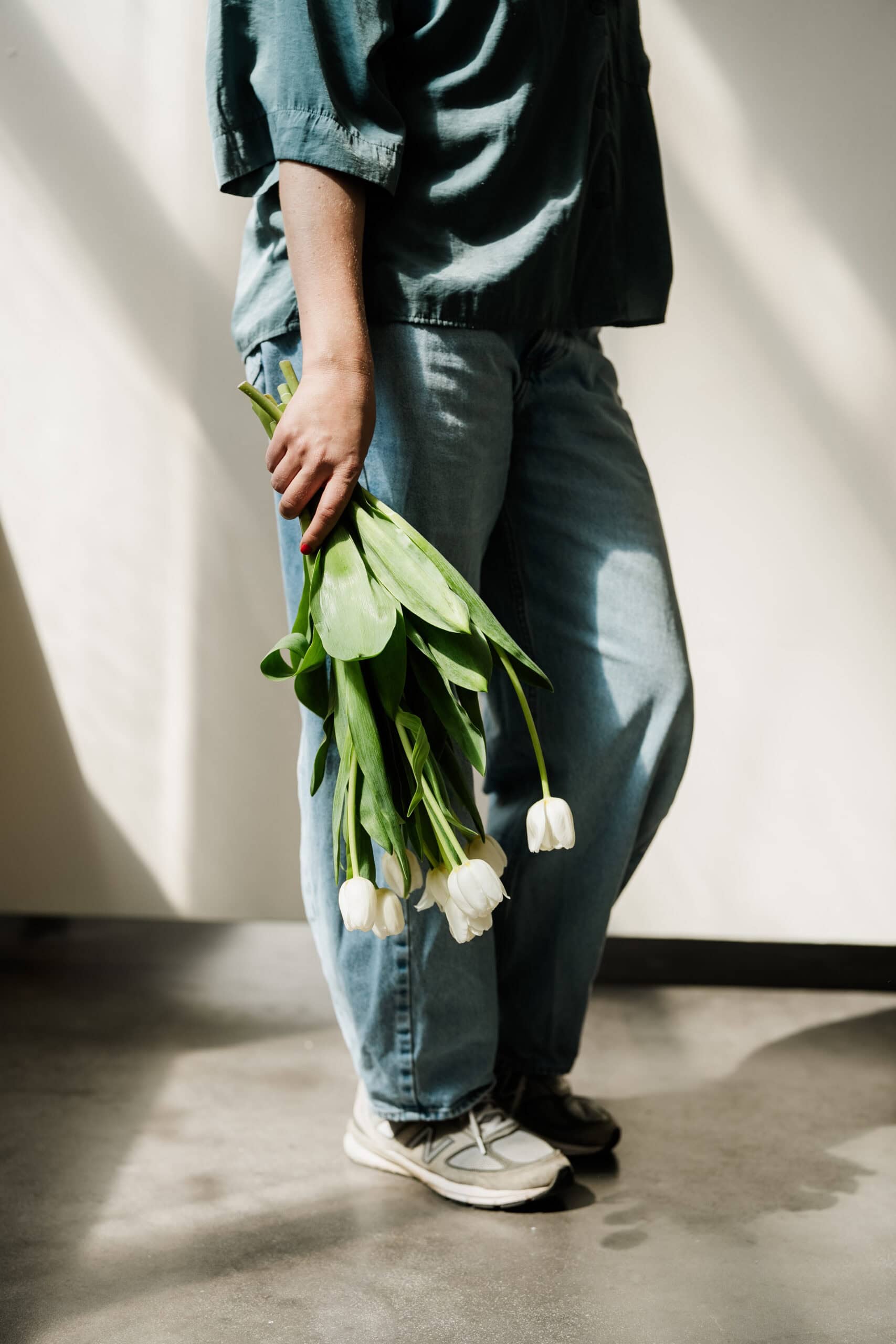 Hochzeitsfotografin Vera hält einen Strauss weisser Tulpen in der Hand beim Shooting in Köln