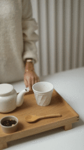 Detailaufnahme von Händen, die an einem Hochzeitsmorgen Tee zubereiten, Hochzeitsreportage NRW in warmem Licht.